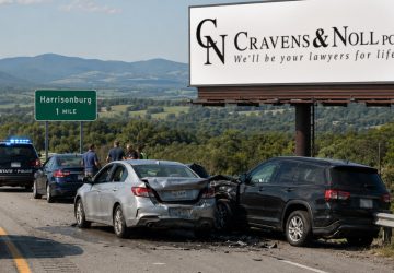 A car accident on a highway near a Harrisonburg sign and a Cravens & Noll law firm billboard