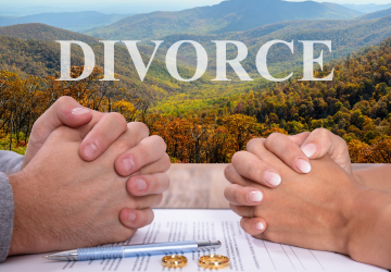 Two pairs of hands clasped over divorce papers and wedding rings